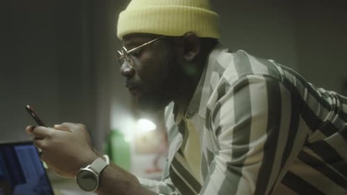 Schwarzer Mann tippt spät im Büro am Telefon