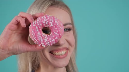 Woman Holds Donut to Her Eye and Smiles