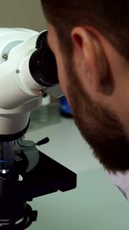Scientist Looking Through Microscope in Bright Lab Setting