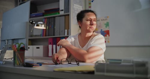 Exhausted Female Teacher Sitting at Computer in Empty Classroom Feeling Stress