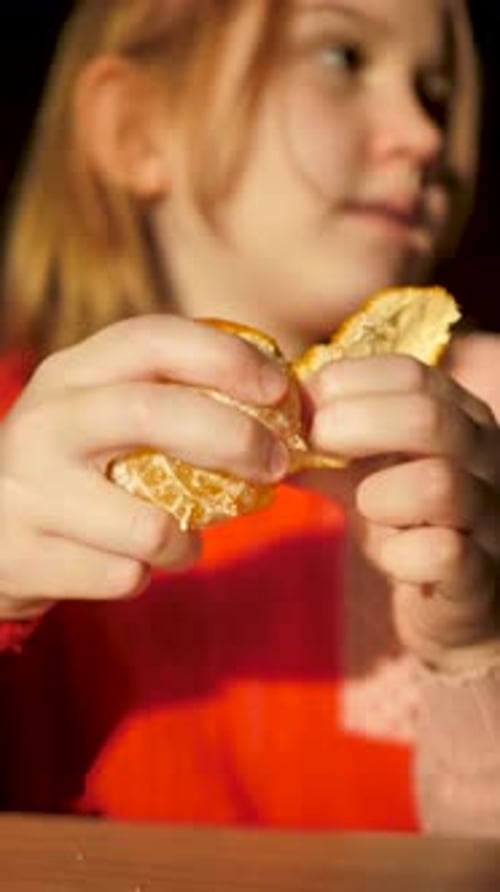 Vertical Girl with Red Hair Peeling a Tangerine Child Sitting at Table and Peeling a Tangerine