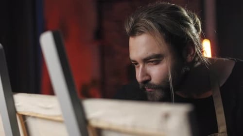 Focused Bearded Man Drawing on Easel in Studio