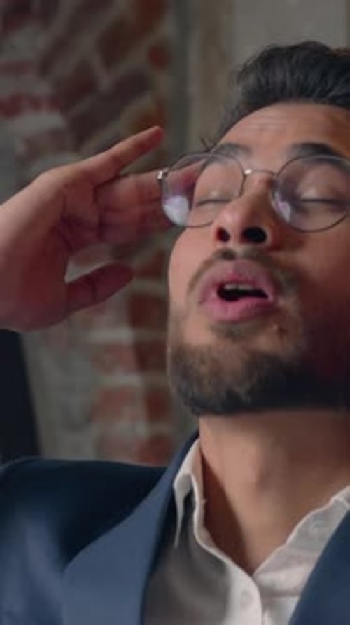 Stressed Young Adult Man Massaging Temples in Office