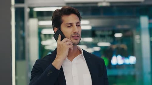 Handsome Man Roaming Around Office Addressing Serious Matters Talking Over the Smartphone