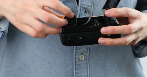 Woman inserting roll of photographic film into photo camera indoors, closeup