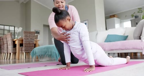 Adult Helps Child with Yoga Pose Indoors