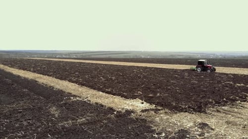 Red tractor plowing the field in Ukraine