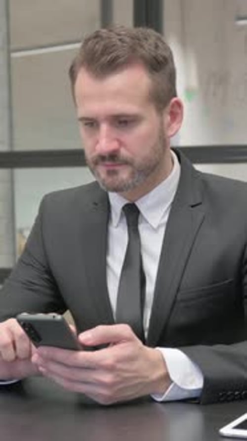 Man in Suit Using Smartphone at Desk