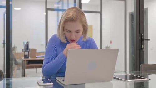 Woman Coughing While Working On Laptop At Desk