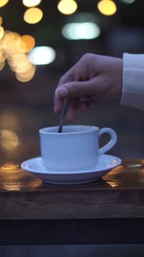 beautiful vertical video portrait of a cup of coffee milk being stirred in a white glass