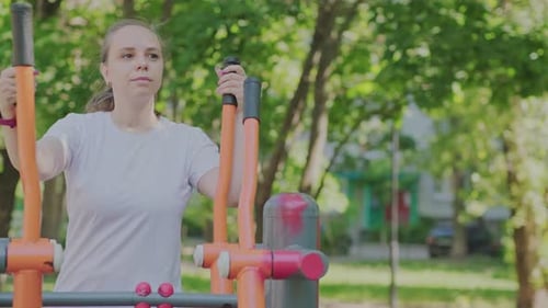 Woman Working Out on Outdoor Exercise Equipment in the Park