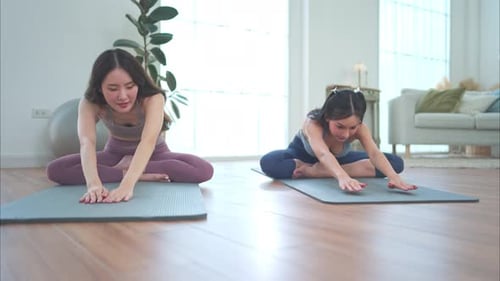 Two Women Practicing Yoga on Mats Indoors