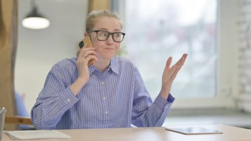 Woman Talking on Cellphone at Table