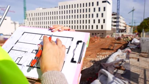 Woman engineer checking building plans at construction site