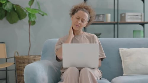 Woman Working on Laptop, Rubbing Her Neck