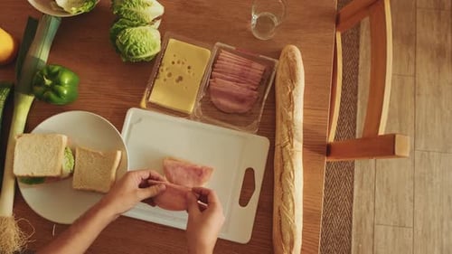 Close-up of hands of young man cooking sandwich standing in the kitchen