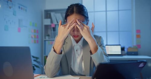 businesswoman rubbing eye feel pain and tired from overwork in office at night.