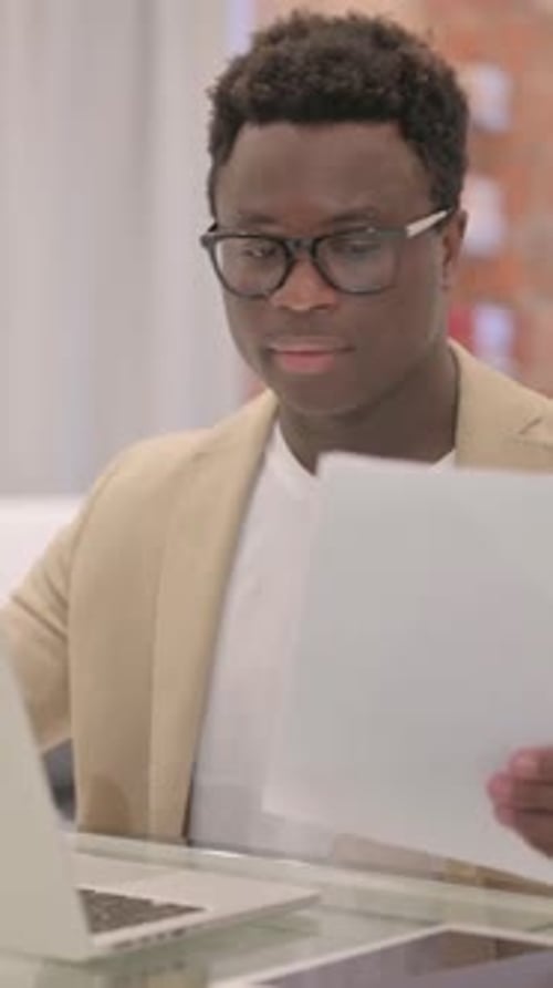 Young Adult Man Reviews Documents at Desk