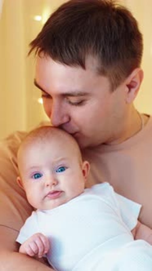 Loving Father Holding and Kissing Baby Indoors