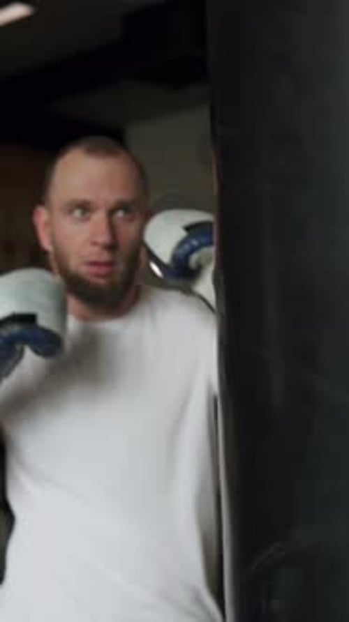 Male fighter in boxing gloves training in gym before fight. Vertical shot.