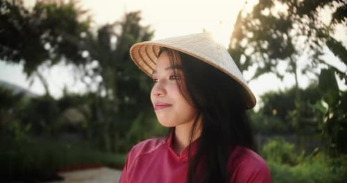 Woman in Traditional Hat Poses Among Greenery