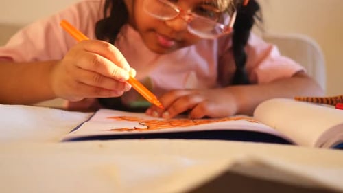 Girl Drawing With an Orange Marker at Home