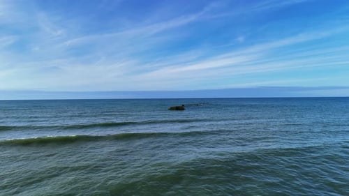 Drone Flight Over the Ocean’s Surface, Capturing Small Waves and a Blue Sky with few clouds