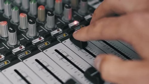 Sound Engineer Adjusting Volume Fader on Console