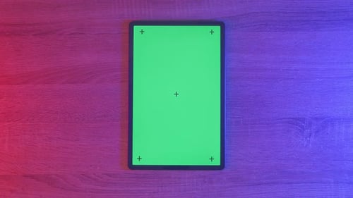Top down view of a mock up green screen tablet on an neon desk, game concept