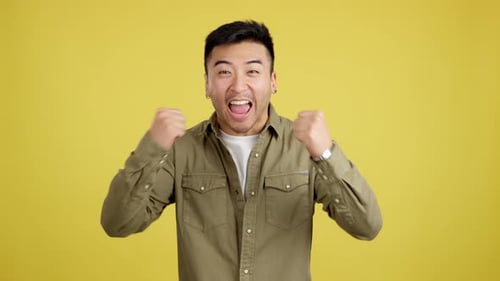 Excited Man Pumps Fists in Studio Setting