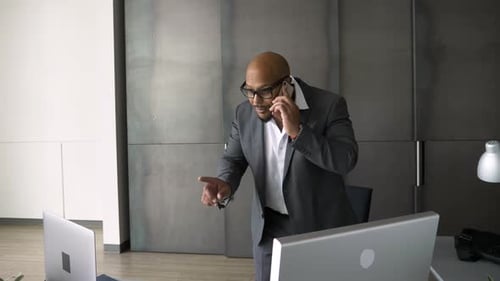 Businessman Talking on Smart Phone at Computer and Laptop in Office Adult