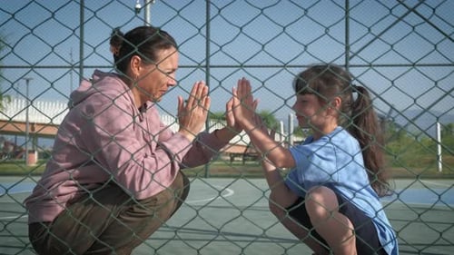 Woman and Girl Play Clapping Game Through Fence