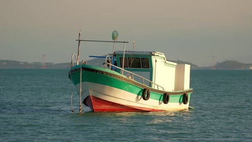 Barco flutua em águas calmas perto da costa durante a luz do início da manhã
