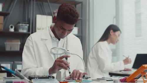 Ingenieur schraubt defektes Bauteil des Smartphones am Tisch ab