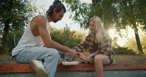 Young Adults Fixing Skateboard in Skate Park