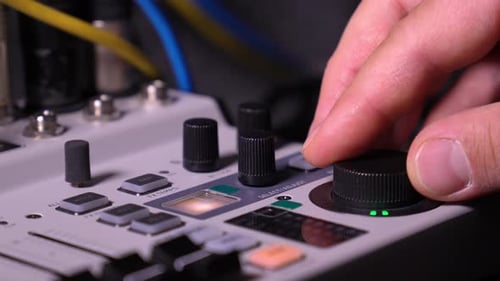 Human finger adjusting audio mixer knob for volume control in recording studio.