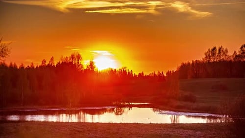 A time-lapse on a sunset above the forest. Lake lies in front of the forest