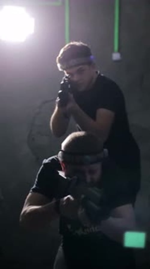 Two People Aiming Weapons in Dark Laser Tag Arena