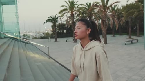 Asian girl wears sportswear, climbs the stairs at morning time on the embankment background
