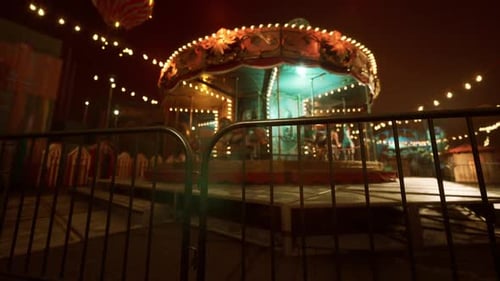 Empty Amusement Park at Night with Illuminated Carousel and Festive Lights