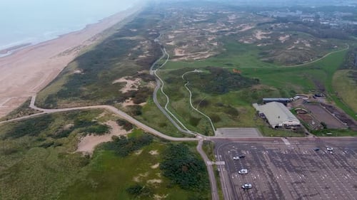 A stunning aerial view of a coastal landscape featuring sandy beaches, grassy dunes winding pathways