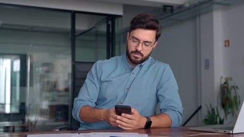 Busy Happy Young Latin Business Man Holding Smartphone Sitting in Office