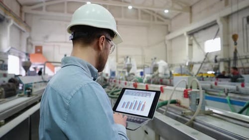 Responsable examinant un document à l'aide d'un ordinateur portable en usine