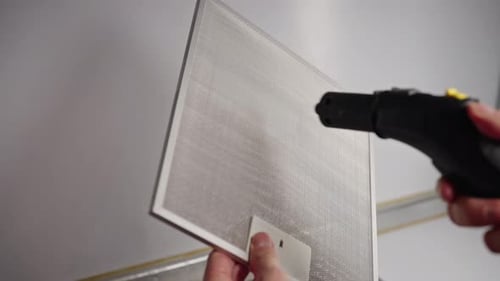 Housewife Using Steam Cleaner Meticulously Cleaning Kitchen Extractor Hood Filter Ensuring Deep