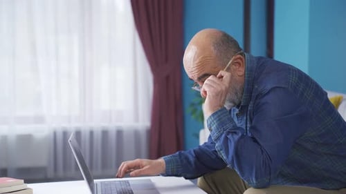 Man With Gray Beard Using Laptop at Home