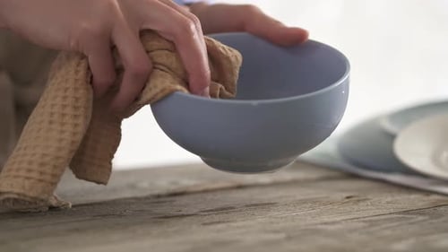 Woman Drying a Blue Bowl with Tan Cloth
