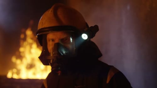 Das Gebäude brennt. Brave Fireman dreht sich um und schaut in die Kamera. Flammenzungen sind Läuse
