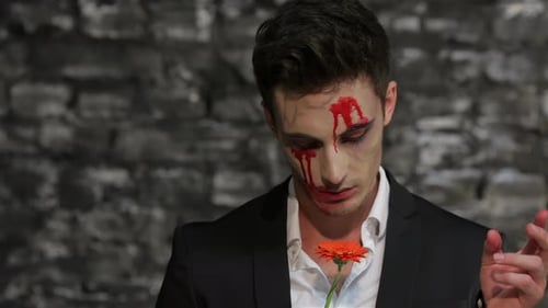 Man with Bloody Makeup Plucking Flower Petals