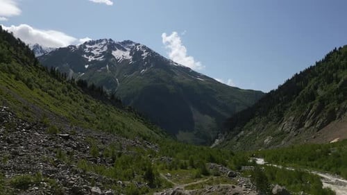 Aerial View of Svaneti Mountains with Snow Peaks Lush Green Valleys Rocky Terrain Clear Sky Summer