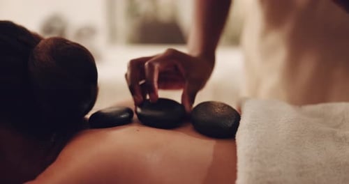 Woman, hands and hot rocks with masseuse for deep tissue massage, physical therapy or zen at spa